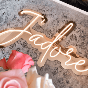 Insegna Neon Led personalizzata rappresentante la scritta "j'adore" su plexiglass oro specchio